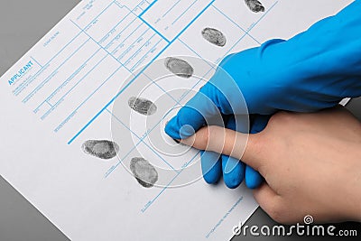 Investigator taking fingerprints of suspect at table. Criminal expertise Stock Photo