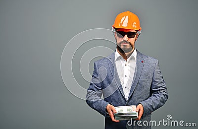 Investment in building or real estate concept. Serious general contractor or real estate investor in building helmet holding dolla Stock Photo