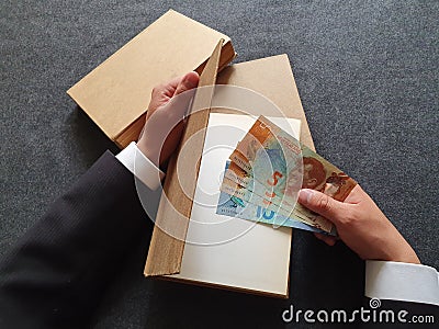 investment in education and knowledge, hands of a man with New Zealand money and books on the table Stock Photo