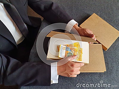 investment in education and knowledge, hands of a man with swiss money and books on the table Stock Photo