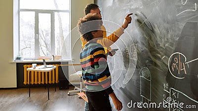 An investment in knowledge pays the best interest. Young male science teacher explaining main rules and formulas in Stock Photo