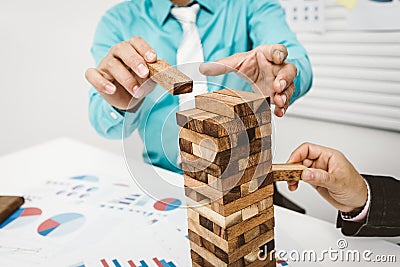 Business man and woman stop wood tower building for tumbledown. Stock Photo