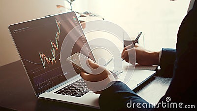 Investment stockbroker predicting bitcoin price trend movement using laptop and phone Stock Photo