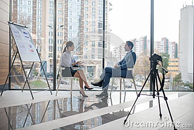 Investor giving the interview to famous journalist sitting near window Stock Photo