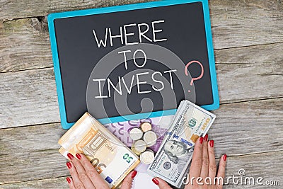 Investor needs inspiration, where to invest question in front of pile of cash money Stock Photo