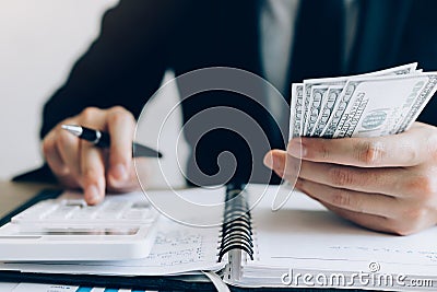 Investors are calculating on calculator investment costs and holding cash notes in hand Stock Photo