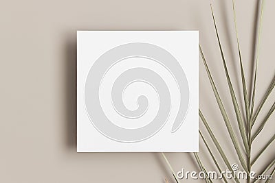 Invitation square card mockup with a palm leaf on a beige table Stock Photo