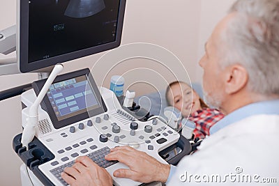Involved aging practitioner using sonography equipment at work Stock Photo