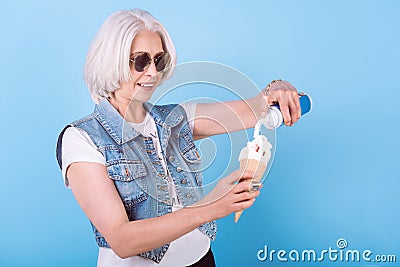 Involved senior woman adding cream in icecream. Stock Photo