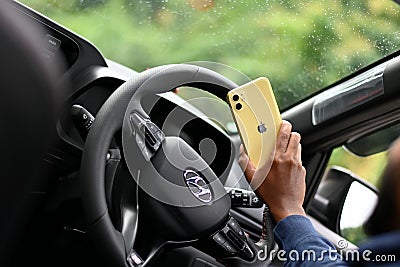 IPhone mobile in a human's hand sitting in Hyundai car Editorial Stock Photo