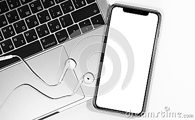 IPhone mockup and Macbook with Apple Earpods closeup at the white background Editorial Stock Photo