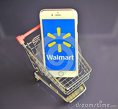 IPhone with Walmart logo in mini shopping cart on table Editorial Stock Photo