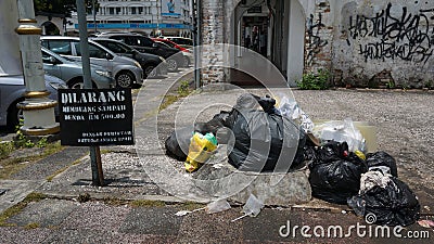 Ignoring signboard warning. Plastic beg and garbage on roadside. Stock Photo