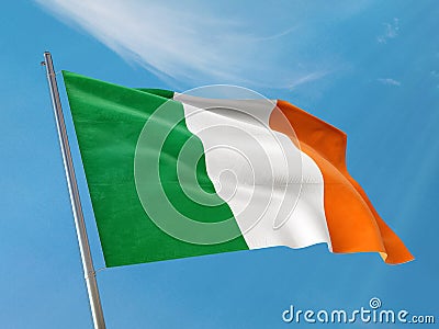Ireland flag on a pole waving. Irish realistic flag waving against clean blue sky. Stock Photo