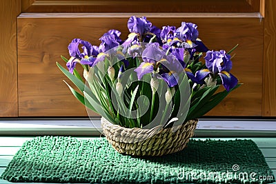 iris bouquet in a basket resting on a green door mat Stock Photo