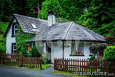 White Irish cottage surrounded by colorful flowers and trees near Powerscourt waterfall near Dublin Stock Photo