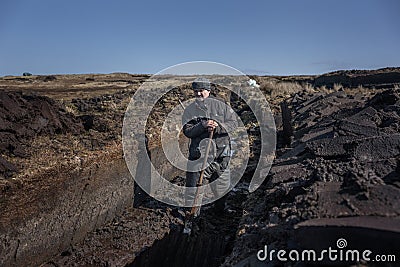 An Irish turf cutter, cutting sods of turf with a sleÃ¡n. Editorial Stock Photo