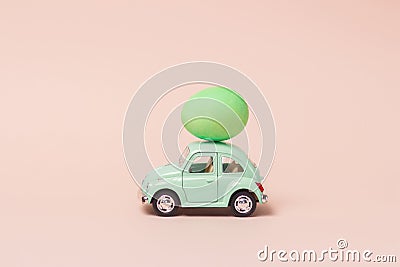 Irkutsk, Russia - january 17, 2021: Light green retro toy car carries easter egg. Minimal easter concept Editorial Stock Photo