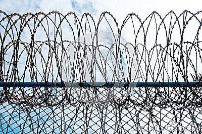 Iron Barbed wire in the blue sky with clouds Stock Photo