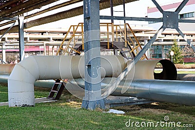 Iron bridge, transition with a ladder and handrails through large thick circles with steam and condensate, pipeline overpass at an Stock Photo