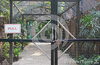 Iron cage door in zoo with `PULL` label Stock Photo