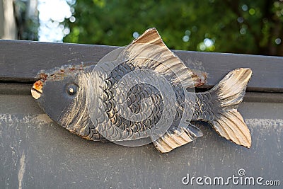 Iron fish on the fence of country house Stock Photo