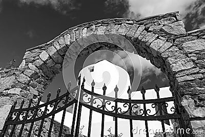 Iron gate and stone arch in Mykonos, Greece. Archway structure or architecture. Whitewashed building on sunny outdoor Stock Photo