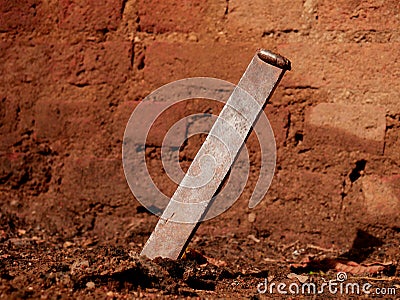 Iron giant nails inserted on soil field at brick wall background Stock Photo