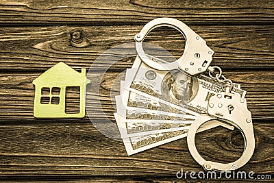 Iron handcuffs, American dollars, a house on a wooden background. Stock Photo