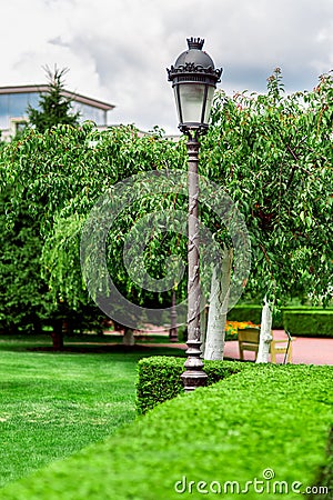 An iron lamppost with a pattern and a lantern with a glass shade. Stock Photo
