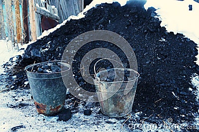 Iron pails with coal near a small pile of coal Stock Photo