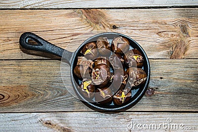 Iron skillet full of roasted chestnuts on a wooden background Stock Photo