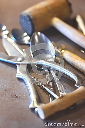 Iron spoons and other tableware lying on a concrete worktop. Stock Photo