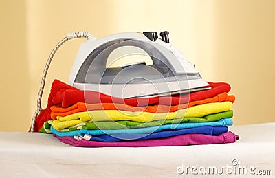 Iron stands with stacks of ironed colored linen. Pile of clothes Stock Photo