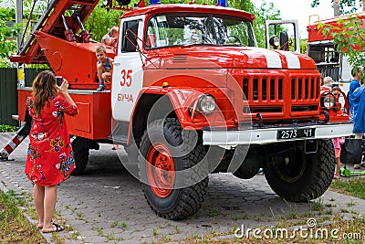 A young mother photographs a child at an exhibition near the fire truck Editorial Stock Photo