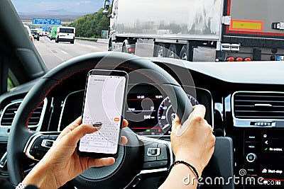 Irresponsible driver texting while driving risking an accident Stock Photo