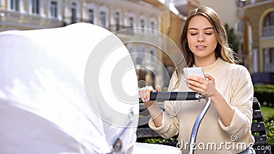 Irresponsible female chatting on smartphone ignoring crying baby in stroller Stock Photo