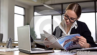 Irresponsible female employee reading magazine in office, avoiding tedious work Stock Photo