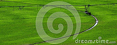 Irrigation Pivot in Lush Green Field with Circle Tracks on Ground Stock Photo