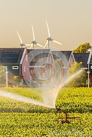 Irrigation sprinkler in front of Dutch houes with solar panels a Stock Photo