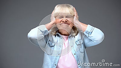 Irritated aged woman closing ears, suffering strong headache, noisy neighbors Stock Photo