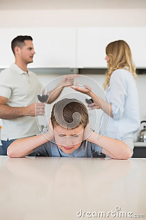 Irritated boy covering ears while parents arguing Stock Photo