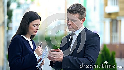 Irritated politician showing PR manager negative election trends on smartphone Stock Photo