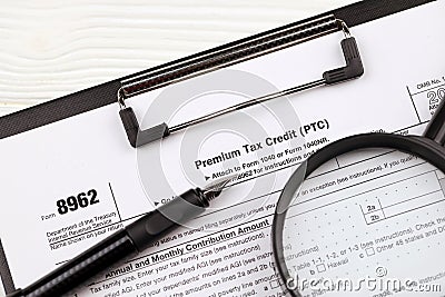 IRS Form 8962 Premium tax cerdit PTC blank on A4 tablet lies on office table with pen and magnifying glass Editorial Stock Photo