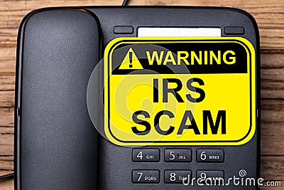 IRS Scam Warning Sign On Landline Phone Stock Photo