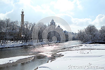 Isar river flows among the cold white landscape of the city of Munich in the snow, a park in winter, the concept of seasonal Stock Photo