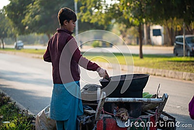 A Young boy is roasting fresh corn for the customers Editorial Stock Photo