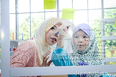 An Islamic teacher taught mathematics to a little girl in the classroom. Stock Photo