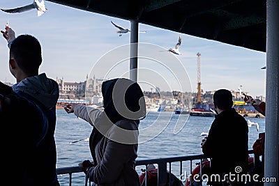 Island Ferry Ada Vapuru. Some of the ferry passengers feed seagulls. Passenger ferryboats from Istanbul sail regularly to the Pr Editorial Stock Photo