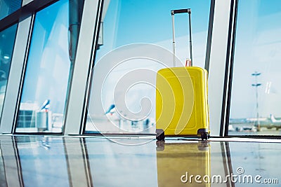 Isolate traveler tourist yellow suitcase at floor airport on background large window, bright luggage waiting in departure lounge Stock Photo